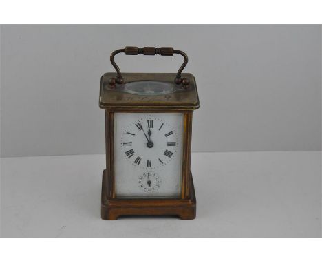 A brass carriage clock, early 20th century, having white enamelled Roman numeral dial with Arabic numeral subsidiary dial, wi