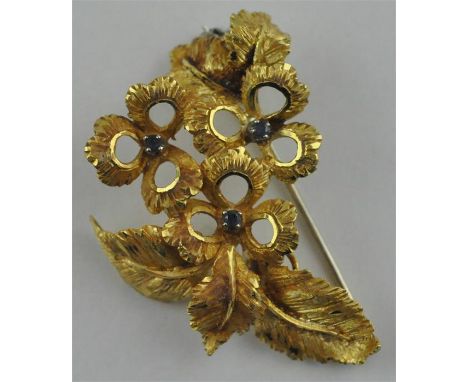 An 18ct. gold floral spray brooch, set three sapphires to centre of flowers, verso stamped ".750", width 4.2 cm, (10.8g), in 