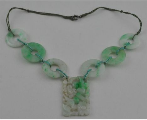 A jade necklace,&nbsp;circa 1920,&nbsp;of mottled green colouration, having rectangular pierced and carved pendant of flowers