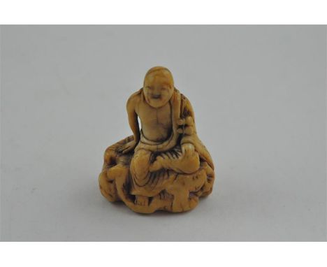 An early Japanese Edo period carved ivory netsuke, of a smiling and seated long haired man. Height 5 cm.