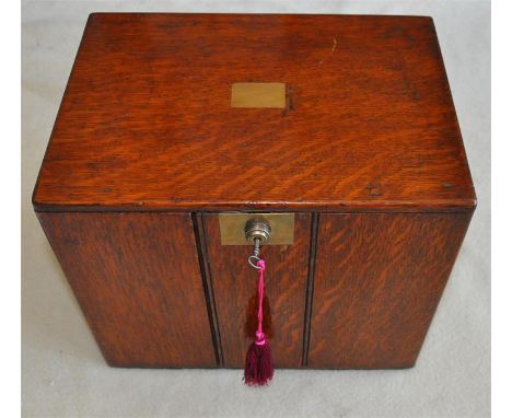 An Army &amp; Navy oak two drawer humidor, early 20th century, having panel doors enclosing two cedar lined divisioned cigar 