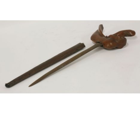 A Malayan kris, the straight watered steel blade with a characteristic carved wooden hilt, contained in its brass wrapped woo