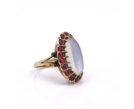 A GOLD, MOONSTONE AND RED GEM SET RINGClaw set with the oval moonstone within a surround of red gems, between split shoulders