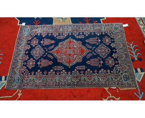 A KESHAN RUG, PERSIANThe dark indigo field with a madder medallion, single bold floral sprays and outer shaped surround of Bo