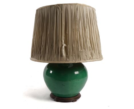 A LARGE GREEN GLAZED POTTERY LAMPMounted on a hardwood stand, with a large pleated shade, 37cm highCondition report:&nbsp;Goo