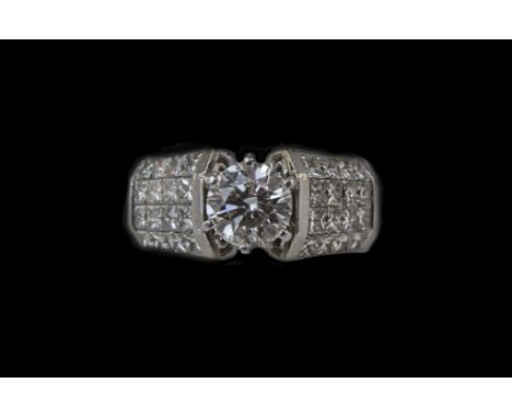 A Platinum Set Fine Single Stone Diamond Ring. The Central Round Brilliant Cut Diamond, Flanked by 24 Baguette Cut Diamonds t