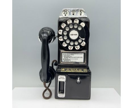 A nostalgic decanter resembling an old black pay phone, complete with a rotary dial, coil slot, and included instructions. Be