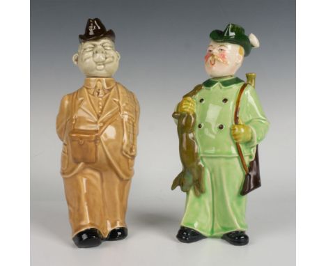 A pair of decanters, one with a blonde man in a green suit holding his recent hunt and rifle, and the other featuring a man i