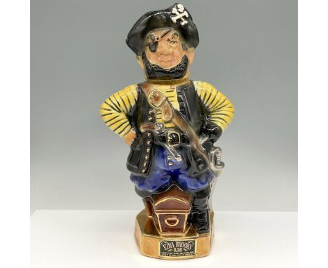 Porcelain pirate bottle is colored in black, yellow and blue standing over his treasure trunk with his peg leg. Marked hand d
