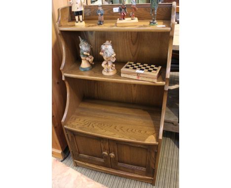 AN ERCOL BOOKCASE UNIT waterfall design, having twin plain panelled cupboard doors to the lower section 