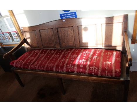 A 19th century oak three-person settle, with panel back having squab seat cushion, supported on plain tapering legs 