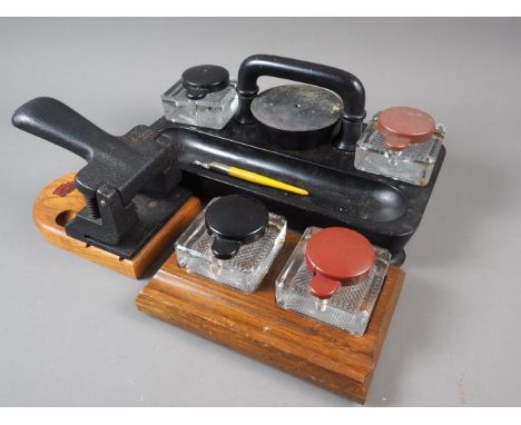 An oak and painted metal desk lamp, two desk top double ink stands and a cast iron hole punch