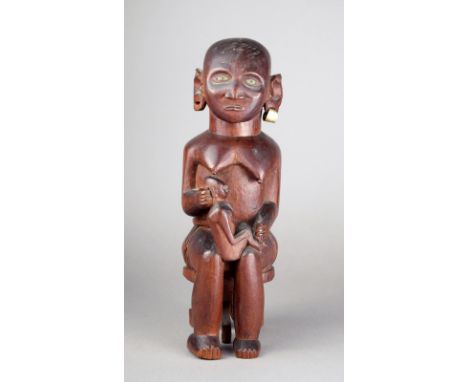 A Kamba maternity figure Kenya wood with inlaid eyes and an aluminium earring, the mother sitting in a tripod stool and with 