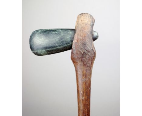 A Papua New Guinea adze with a greenstone blade and a wood shaft, 71.5cm long.