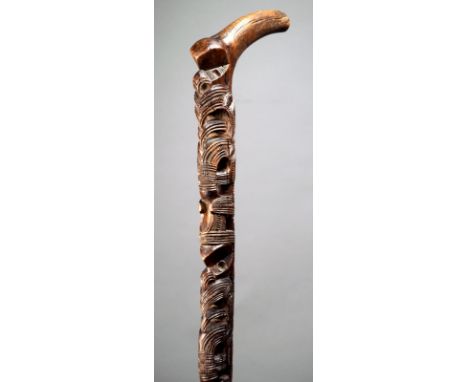 A Maori walking stick New Zealand wood, carved and pierced four tiki figures, previously with inlaid eyes, with a curved hand