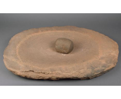 A Neolithic grinding basin and pestle North Africa, 8th - 7th Millenium BC sandstone with a shallow recess, 63cm long, 41cm w