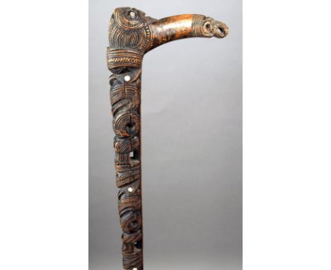 A Maori walking stick New Zealand wood and haliotis shell, the stem with four tiki figures and one to the top, the curved han