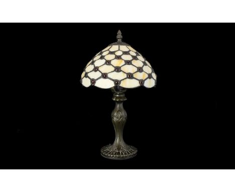 A Reproduction Tiffany Style Table Lamp Raised on a art nouveau style cast metal base, the leaded and glazed shade in cream s