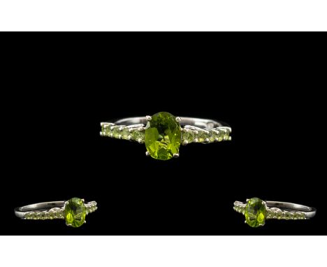 Peridot Classic Style Ring, a central, oval cut peridot with further small round cuts along the shoulders of the band, totall