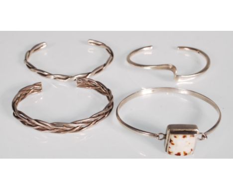 A selection of four silver bangle bracelets to include a plaited bangle, a twist design bangle, a bangle set with a square sh