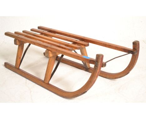 A vintage 20th Century Davos Germina wooden toboggan / sled having metal runners. Measures 24cm high x 43cm wide x 82cm long.
