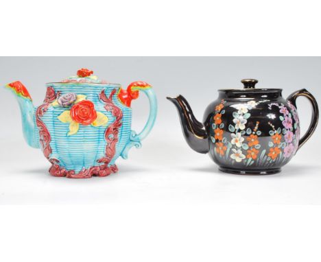 A World War II teapot with a black ground, hand decorated with flowers, the lid having inscribed' U.S.A. BRITAIN AND DEMOCRAC