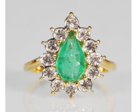 An unmarked but tests as 9ct yellow gold ring set with a central cut green glass stone with a halo of white stones on a taper