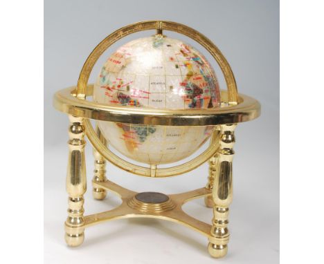 A vintage style lapis lazuli desk top globe having brass mounts with inset semi precious stones on a neutral ground 