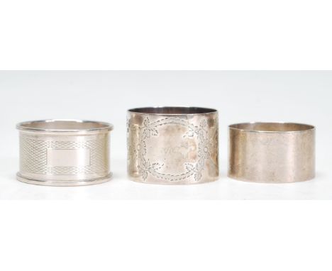 A group of three 20th Century silver hallmarked napkin rings to include an engine turned napkin ring with unmarked rectangula