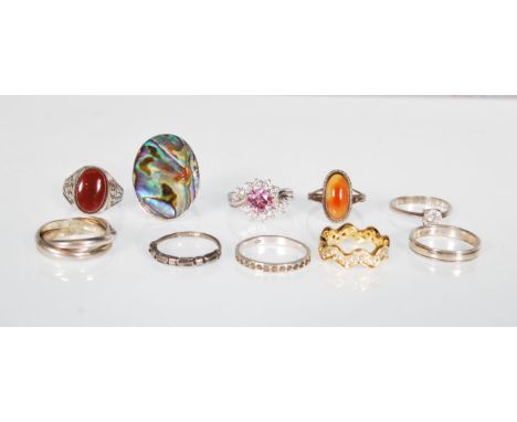 A collection of silver rings to include an oval panel ring set with abalone, a pink and white stone dress ring, a white stone