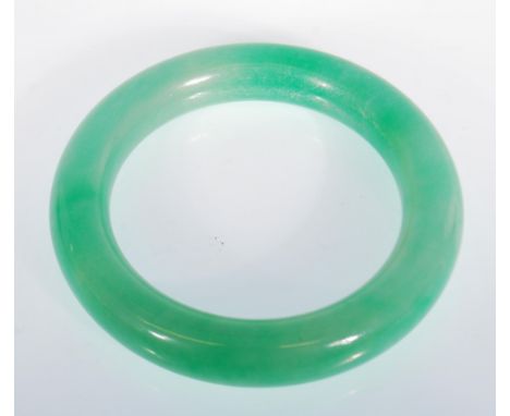 A Chinese green jade bangle of typical round form. Interior diameter 5.9g. Measures 99.4g.&nbsp;