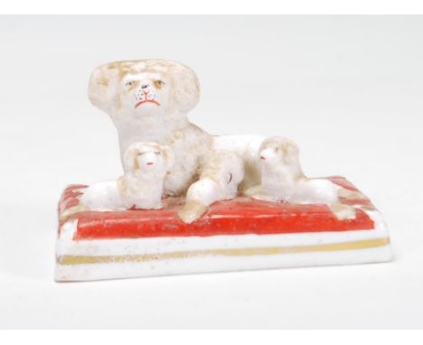 A rare 19th Century Victorian Staffordshire ceramic figurine of a poodle with a group of three puppies on red velvet cushion.