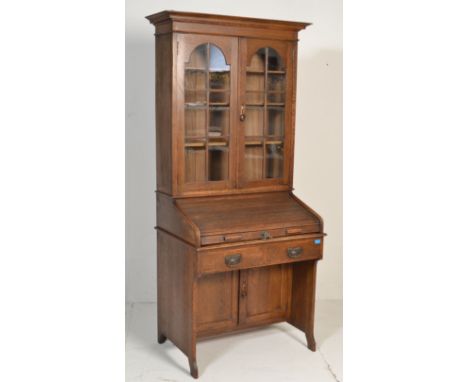 An early 20th century Arts and Crafts ' The Lebus Desk ' oak tambour roll top bureau bookcase, glazed doors with adjustable s