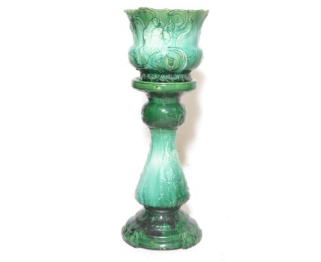 An early 20th century green majolica planter and stand in the Art Nouveau manner having flower and vine decoration. The under