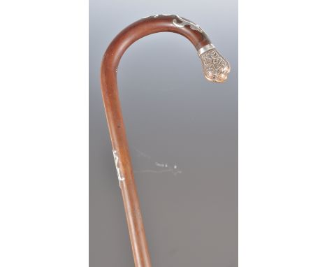 A 19th Century Victorian walking stick cane having a shaped wooden handle with ornate silver white metal ribbon mounts and sc