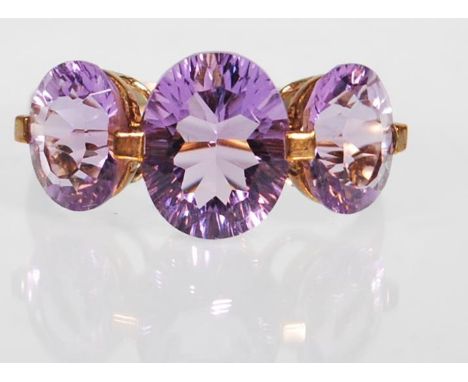 A 9ct gold hallmarked amethyst trilogy dress ring, large central oval cut stone flanked by two smaller oval cut stones. Size 