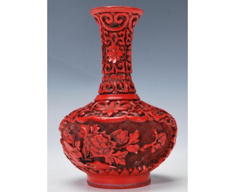 A Chinese 20th Century red cinnabar vase having a waisted neck and squat globular body decorated with flowers and scroll deco