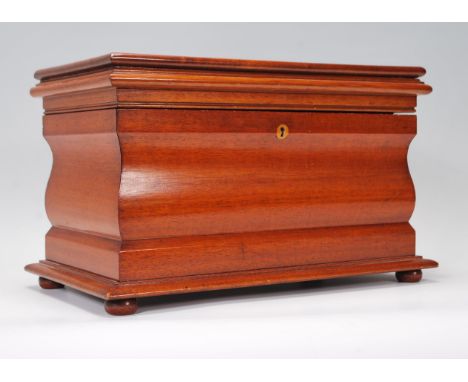 A mahogany tea caddy of sarcophagus form, hinged lid opening to reveal two lidded compartments and space for tea mixing bowl,