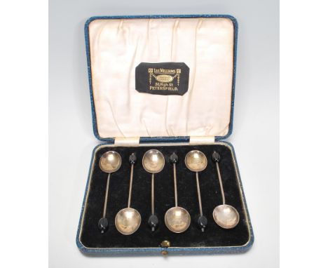 A set of six cased silver hallmarked tea spoons with black coffee bean finials, set within a blue leatherette case marked Leo