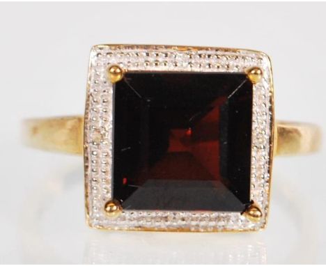 A 9ct gold Princess cut garnet and diamond dress ring, stamped 375 large central garnet stone surrounded by a border of diamo