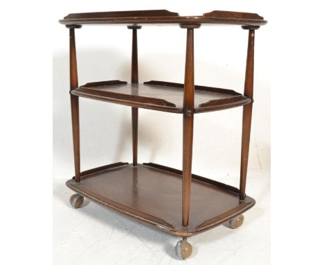 A vintage mid 20th Century Ercol three tier trolley, with a raised gallery on turned supports terminating in castors.&nbsp; M