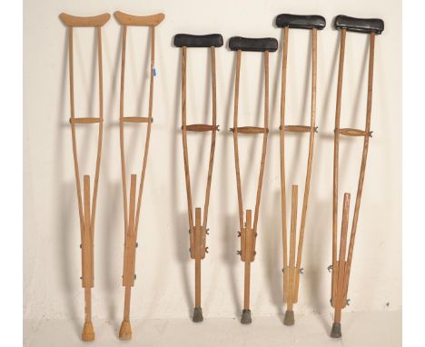 Three pairs of vintage 20th Century World War II era wooden crutches consisting of two pairs of oak construction and a pair o