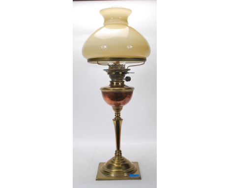 An 20th Century antique brass oil lamp having a square base with knopped column, copper reservoir and cream bulbous form shad