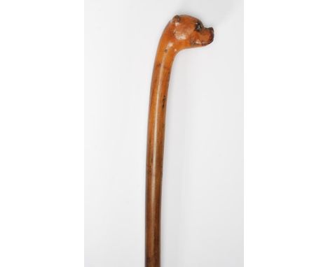 A 19th Century child's walking stick cane of tapering form having the top carved in the form of a boxer dog set with glass ey