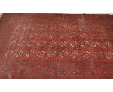 A large vintage early 20th Century Persian style floor rug on red group with large central geometric panel, borders with tass