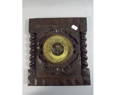 A Carved Oak Wall Hanging Aneroid Barometer with Barley Twist Supports.