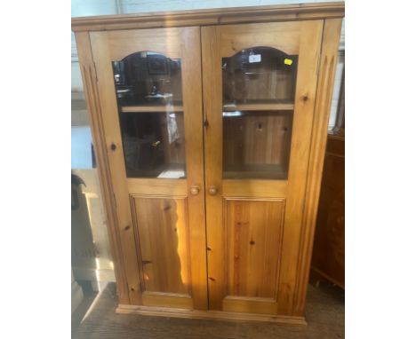 A Modern Pine Glazed Cupboard. The pair of doors enclosing three shelves. Fitted with a light. 127cm x 91cm x 35.5cm 