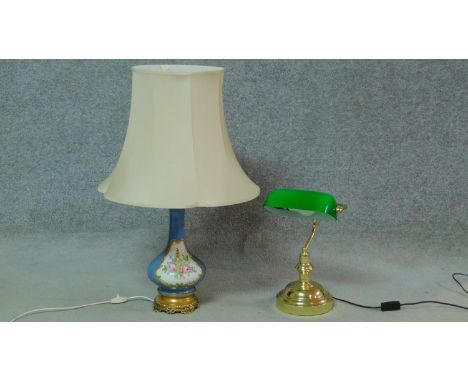 A green glass and brass bankers desk lamp along with a hand painted and gilded porcelain floral design lamp on a gilt metal r