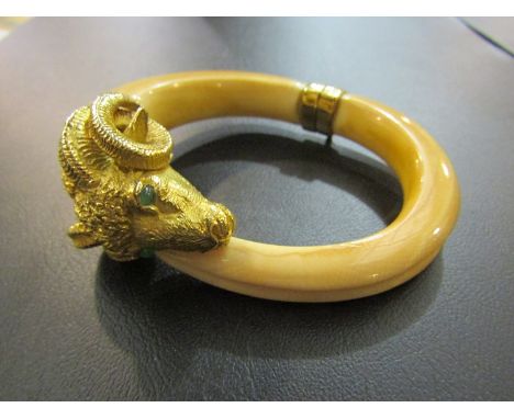A boors tusk bangle, with rams head terminal set with emerald eyes, unmarked