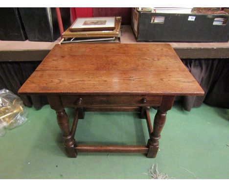 In the manner of Titchmarsh and Goodwin a 17th Century style plank top oak lamp table with single frieze drawer on turned leg